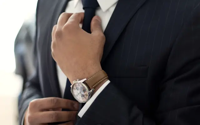 Man in a dark suit adjusting his tie